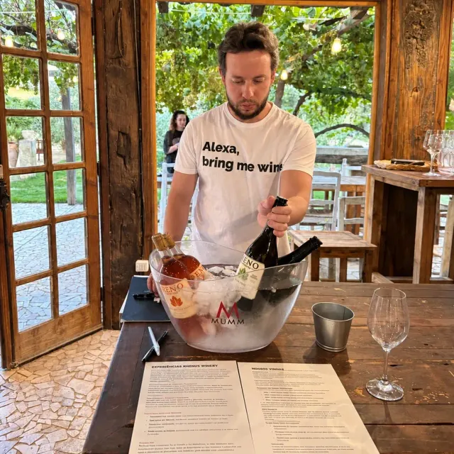Botellas en una hielera sobre una mesa rústica con las cartas de las experiencias Rhenus Winery